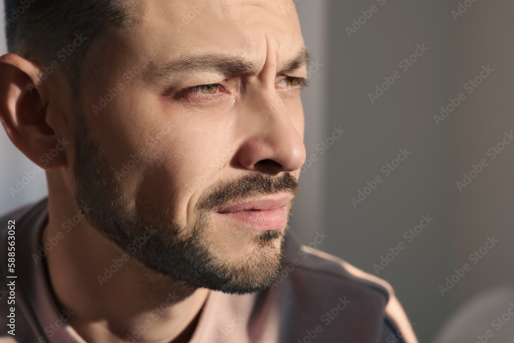 Fototapeta premium Upset man crying indoors, closeup. Loneliness concept