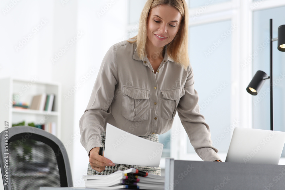 Happy woman working with documents at table in modern office Happy woman working with documents at table in modern office