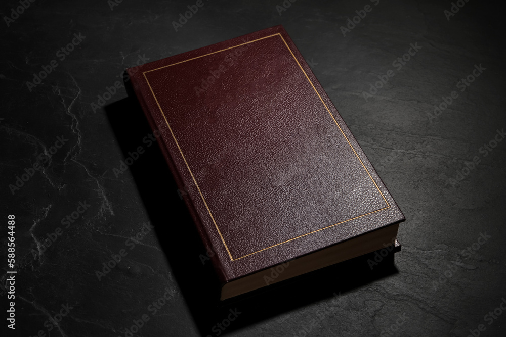 One old hardcover book on black textured table One old hardcover book on black textured table