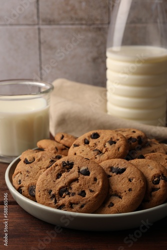 Delicious chocolate chip cookies and milk on wooden table, closeup