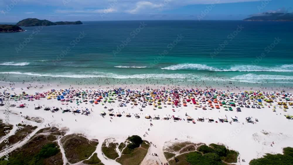 Vista do drone sobre a praia cheia de turistas e guarda-sol, mar limpo e areia branca na verão na cidade de Cabo Frio, Rio de Janeiro, Brasil Vista do drone sobre a praia cheia de turistas e guarda-sol, mar limpo e areia branca na verão na cidade de Cabo Frio, Rio de Janeiro, Brasil