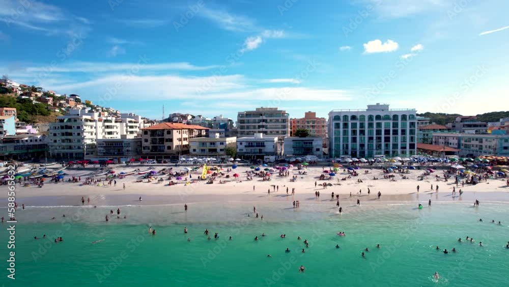Vista do drone sobre a praia cheia de turistas e guarda-sol, mar limpo e areia branca na verão na cidade de Cabo Frio, Rio de Janeiro, Brasil Vista do drone sobre a praia cheia de turistas e guarda-sol, mar limpo e areia branca na verão na cidade de Cabo Frio, Rio de Janeiro, Brasil