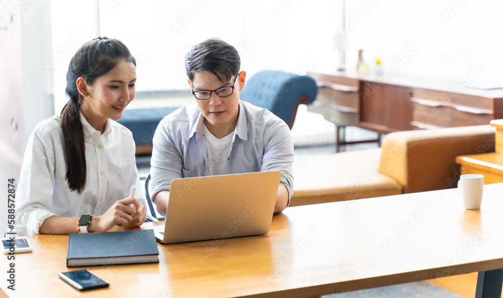Business meeting and conference at home. Asian businessman and businesswoman working on laptop computer together at home Business meeting and conference at home. Asian businessman and businesswoman working on laptop computer together at home