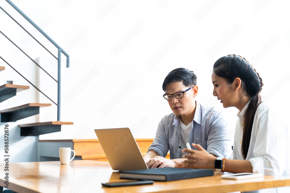 Business meeting and conference at home. Asian businessman and businesswoman working on laptop computer together at home Business meeting and conference at home. Asian businessman and businesswoman working on laptop computer together at home