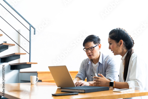 Business meeting and conference at home. Asian businessman and businesswoman working on laptop computer together at home