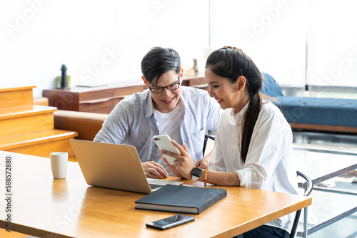 Business meeting and conference at home. Asian businessman and businesswoman working on laptop computer together at home