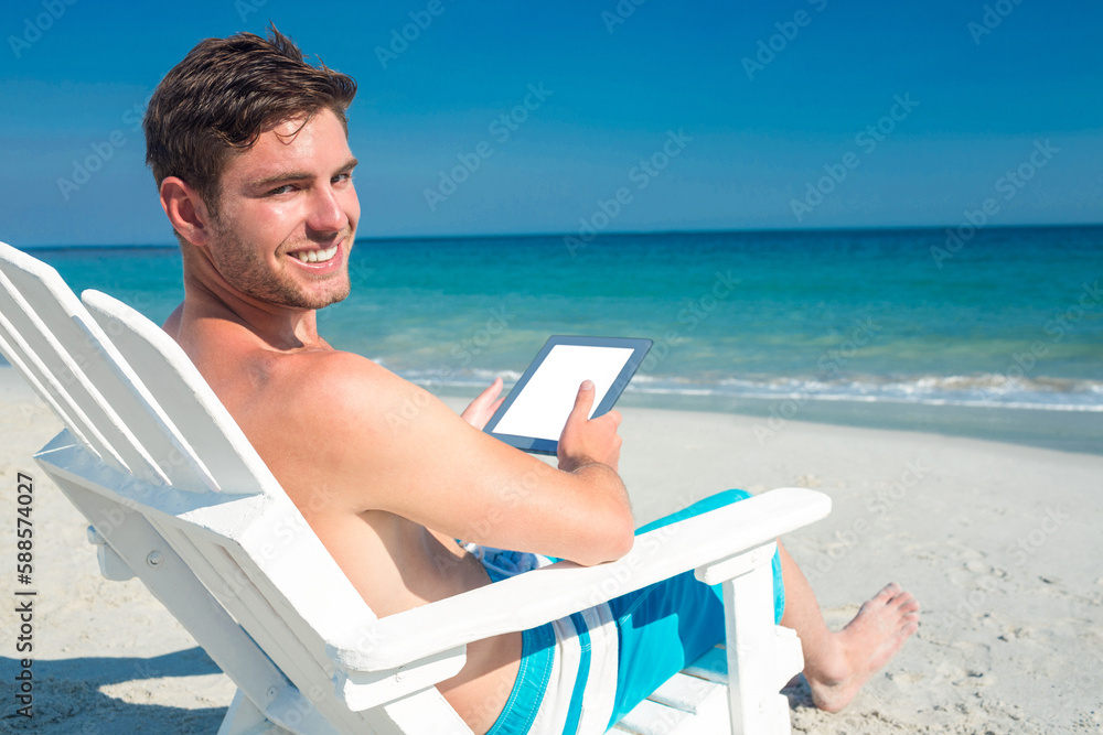 Man using digital tablet on deck chair at the beach