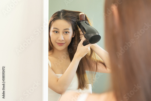 Hair Dryer, happy, asian young woman, girl hand in using hairdryer to dry, blowing long blonde straight after shower at home. Hairdressing, hair treatment and beauty health care.