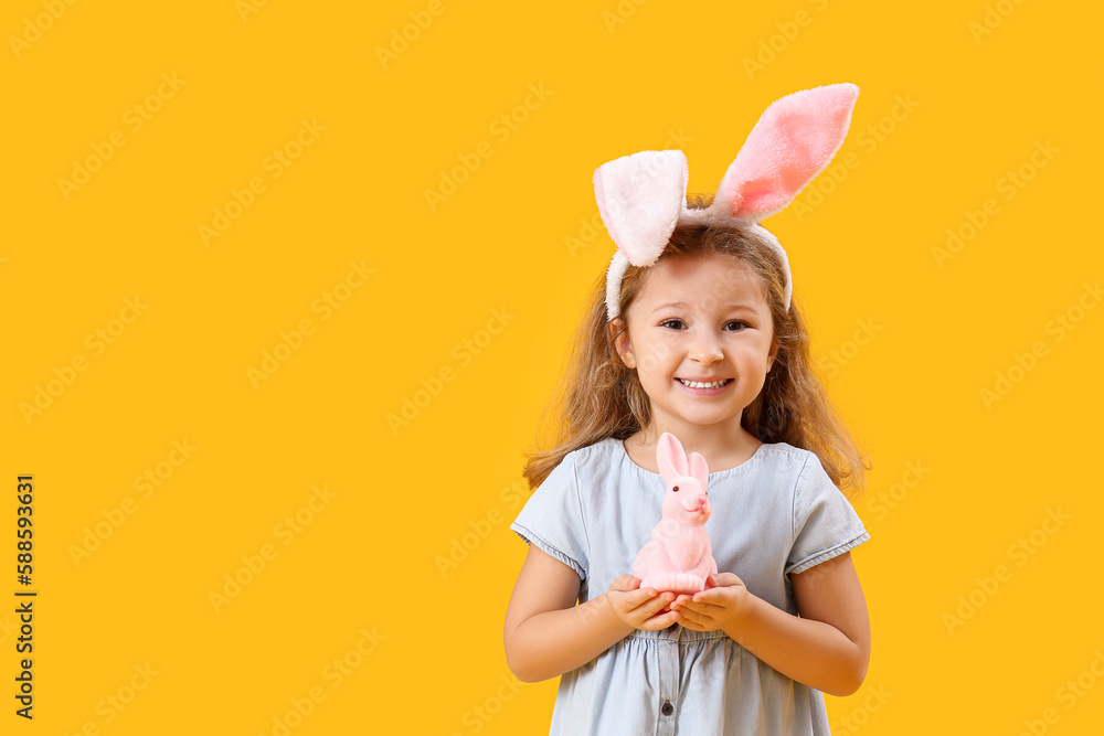 Little girl in bunny ears with Easter rabbit on yellow background Little girl in bunny ears with Easter rabbit on yellow background