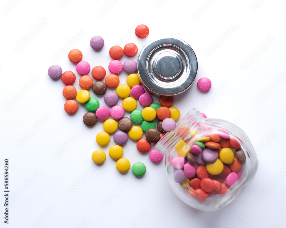 Multicolored candies in a glass jar isolated on a white background