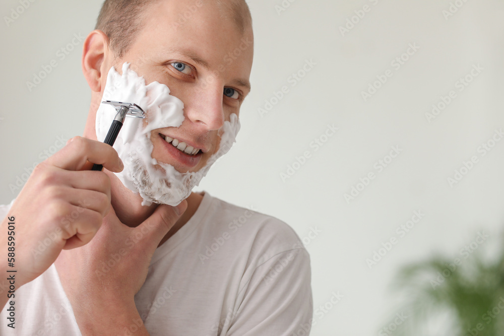 Young man shaving in bathroom