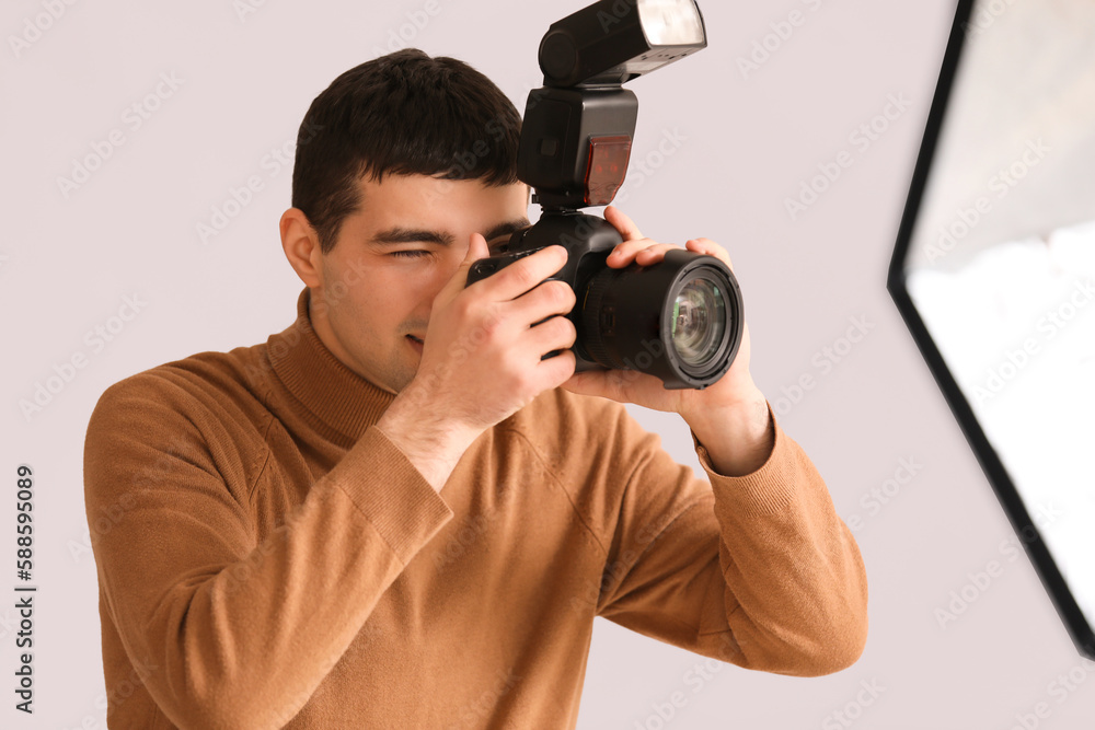 Fototapeta premium Young male photographer with professional camera in studio, closeup