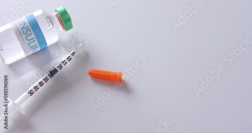 Close up of insulin vial and syringe on white background with copy space, slow motion photo