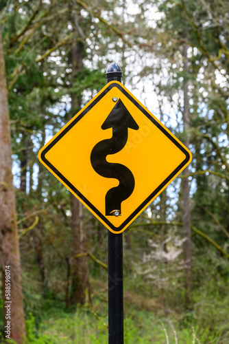 Curves ahead traffic sign in a wooded environment 