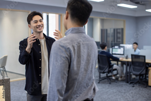 Cheerful Chinese business people greeting in office