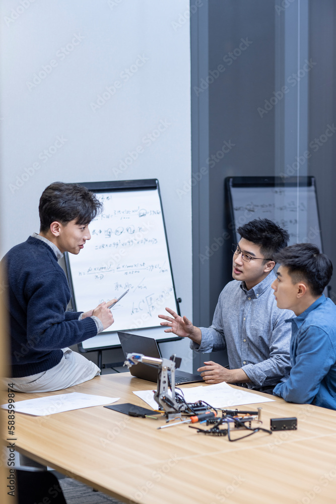 Confident Chinese designers checking a robotic arm Confident Chinese designers checking a robotic arm