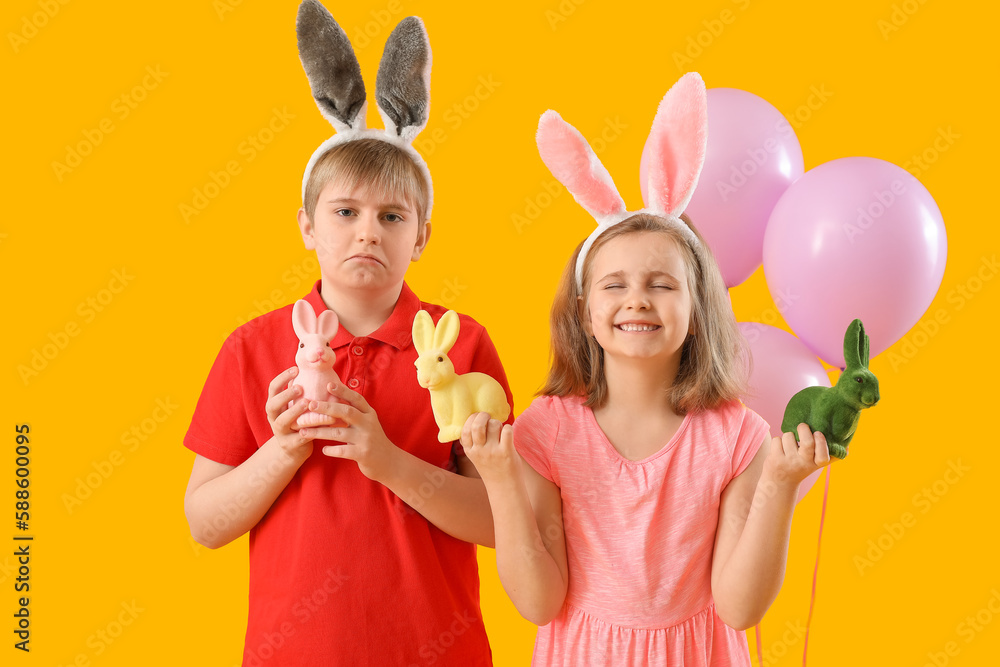Little children in bunny ears with Easter rabbits and balloons on yellow background Little children in bunny ears with Easter rabbits and balloons on yellow background