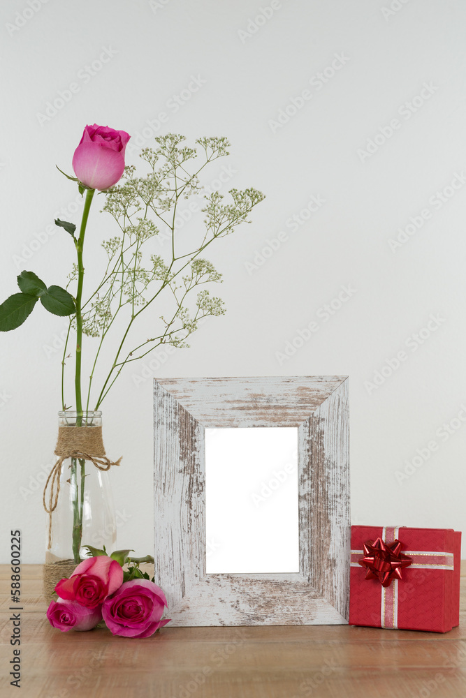Fototapeta premium Rose flower in glass vase, photo frame and gift box