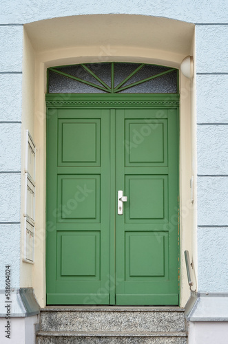 View of old building with green wooden door and steps