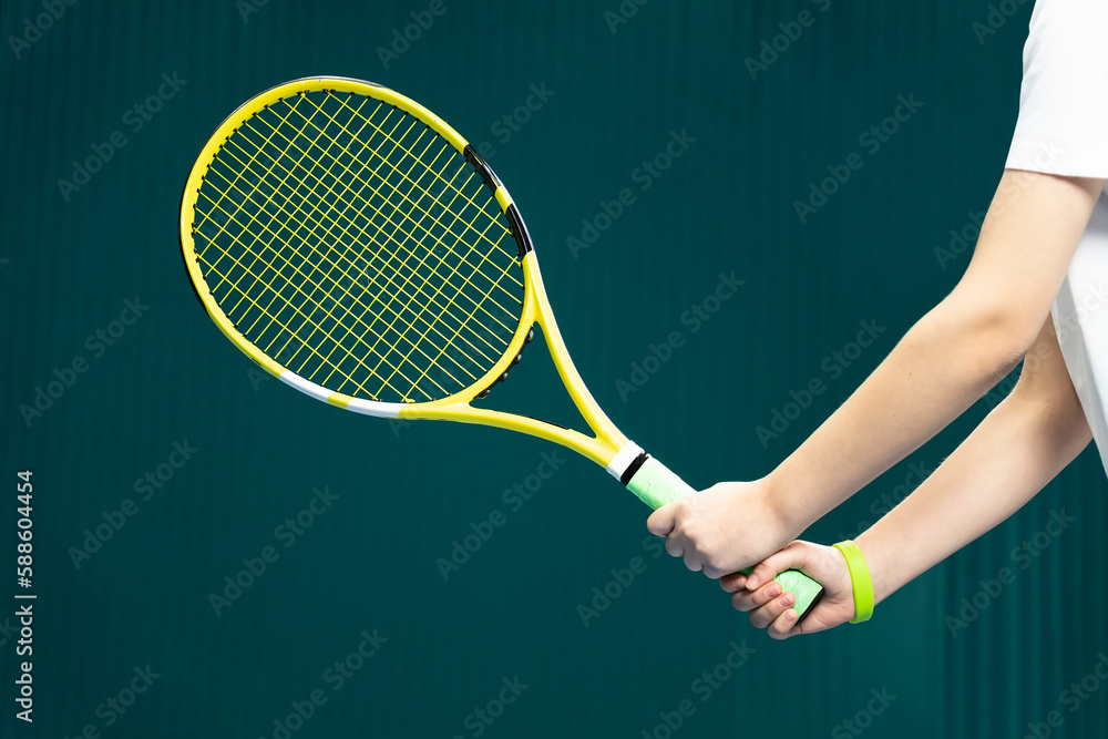 tennis racket in hands of a girl close - up on a dark green background . the game of tennis