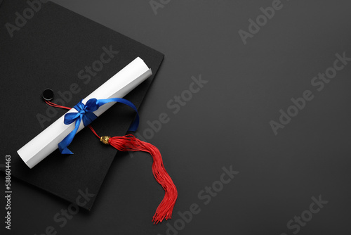 Diploma with blue ribbon and graduation hat on black background