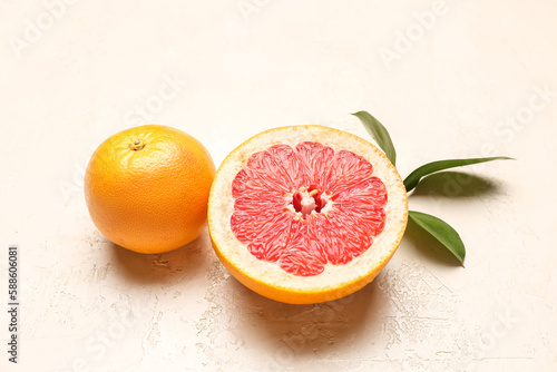 Ripe grapefruits and plant branch on light background