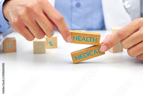 Hand of doctor holding a wooden block cube with text and behind it is a wooden block with blurred icon symbol. Medical and health concept.