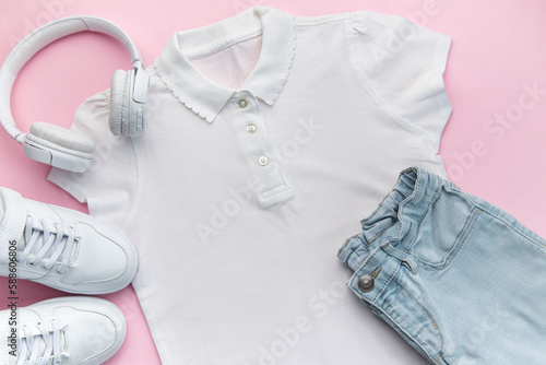 Child's t-shirt, shoes and headphones on pink backgrund