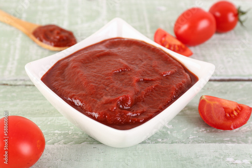 Bowl of tasty tomato paste on green wooden background