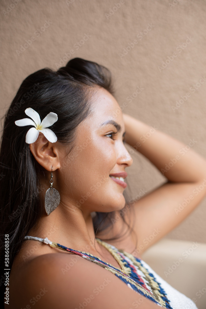 Close-up portrait of face in profile of beautiful young happy woman with white flower in her hair. Tourism and travel. 