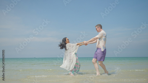 Couples hold hands and walk along the beach on their summer vacation and they smile and have fun on vacation.