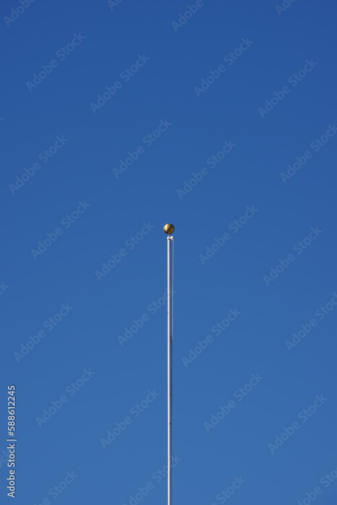 Single flagpole under blue sky