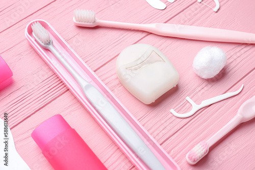 Composition with dental floss, toothpicks and brushes on pink wooden background