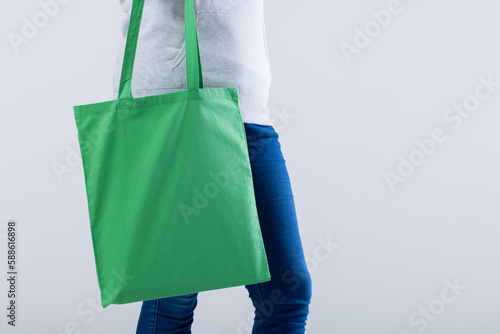 Caucasian woman holding green canvas bag with copy space on grey background