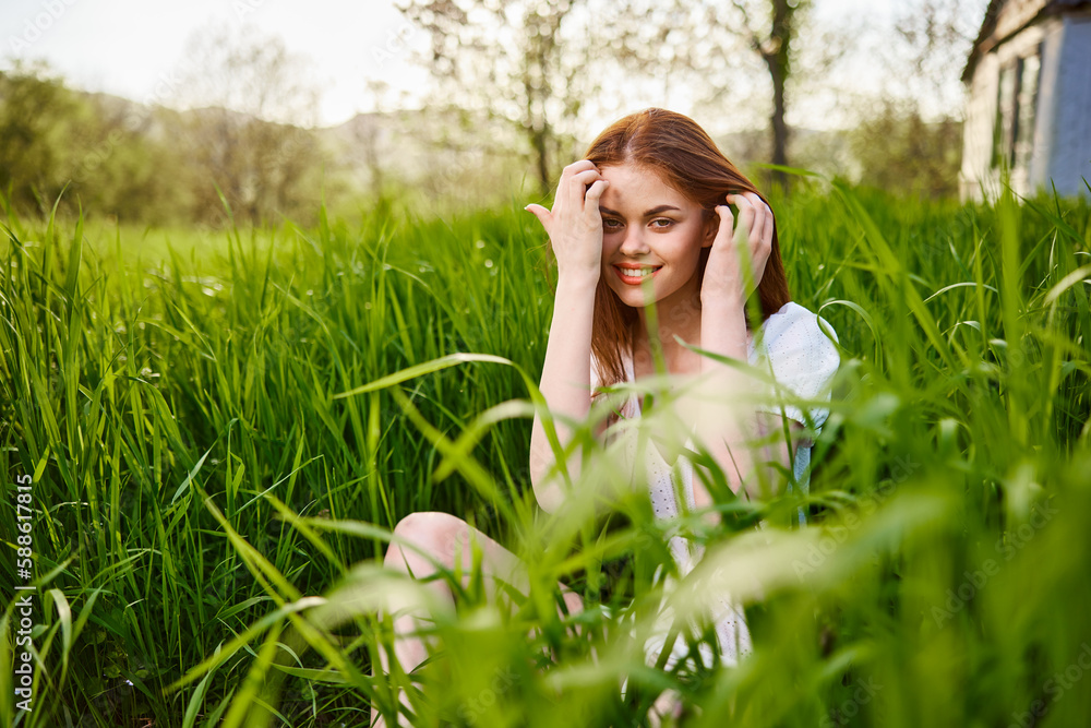a young woman sitting resting in the tall grass straightening her hair a young woman sitting resting in the tall grass straightening her hair