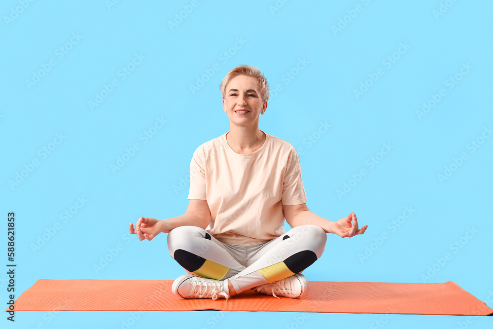 Mature woman meditating on light blue background