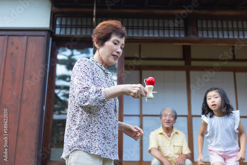 孫にけん玉を披露する祖母と見まもる祖父