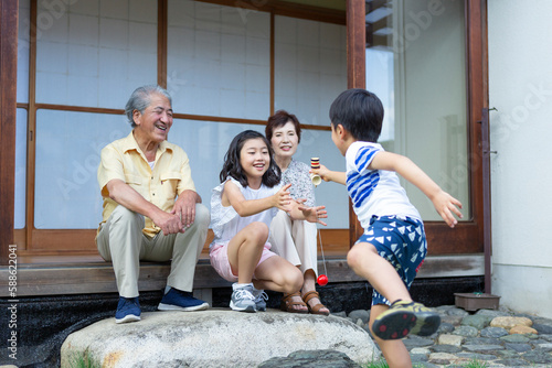 けん玉をする男の子と見守る祖父母と姉