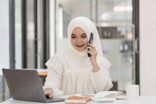 Happy Asian Muslim Woman working at desk in office, Businesswoman and education online concept. 