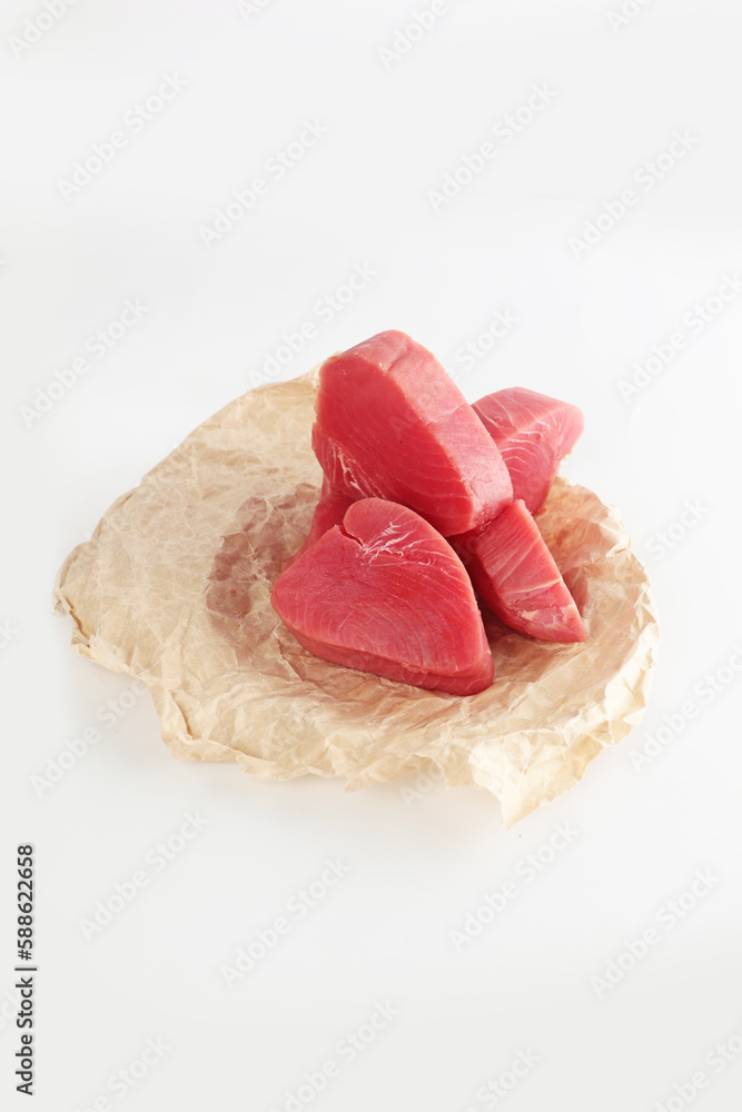 Pieces of raw tuna meat. Tuna pieces for steaks on craft paper. Isolated object. Photo on a white background.Isolated object.Copy space.Vertical photo. Pieces of raw tuna meat. Tuna pieces for steaks on craft paper. Isolated object. Photo on a white background.Isolated object.Copy space.Vertical photo.