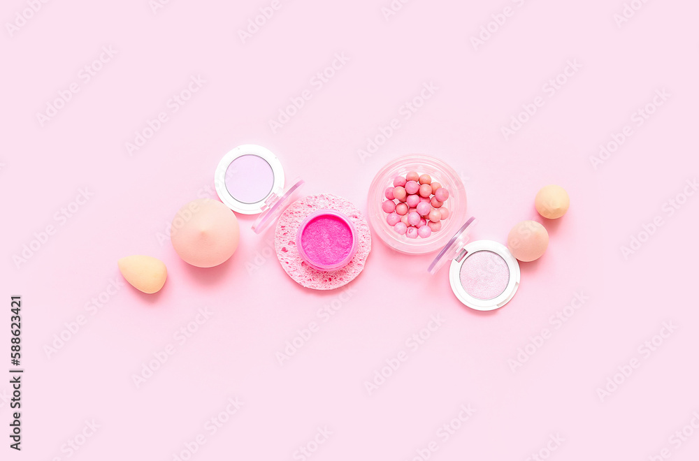 Fototapeta premium Decorative cosmetics with makeup sponges on pink background