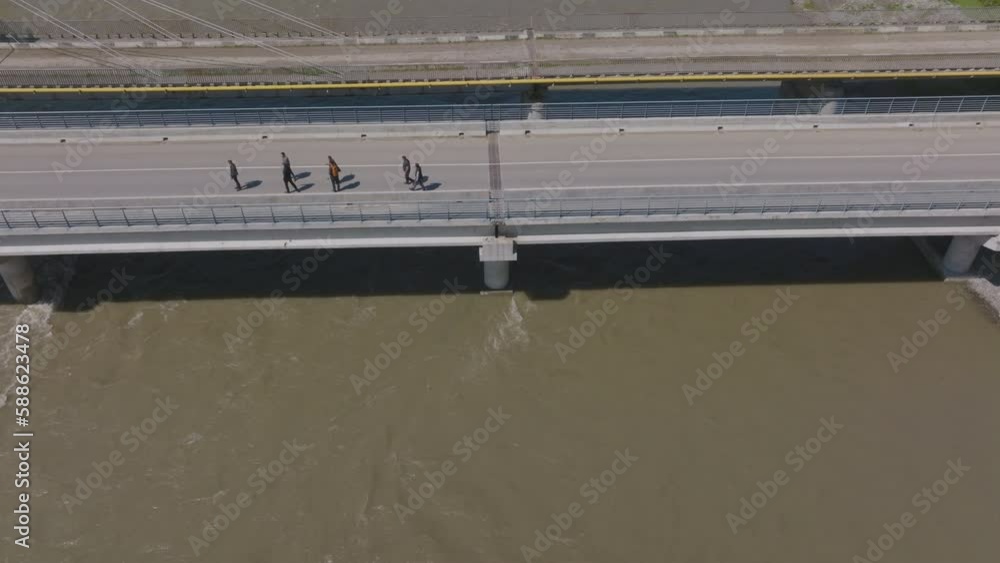 Aerial shot of a group of people walking across a bridge and then turning around Aerial shot of a group of people walking across a bridge and then turning around