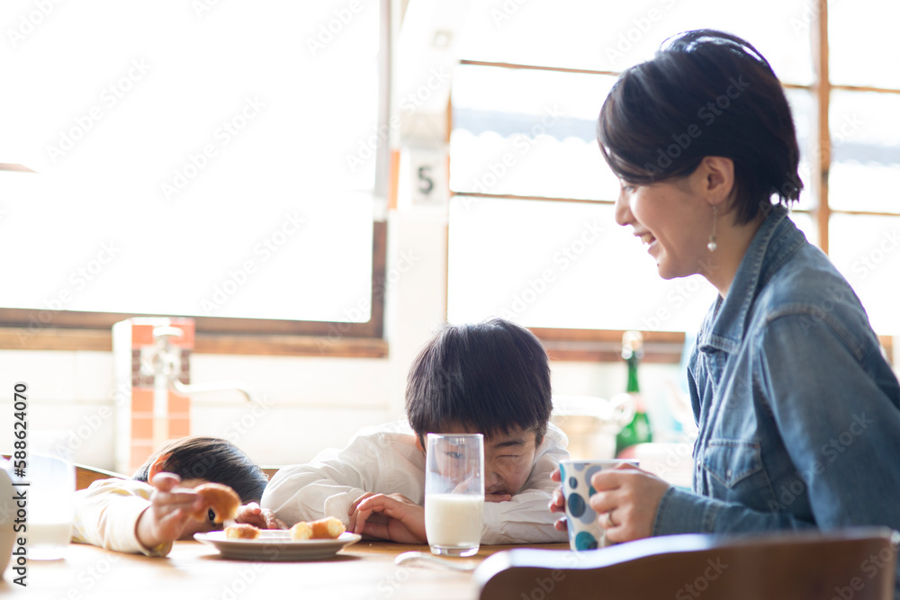 キッチンのテーブルでおやつを食べる兄弟と母親