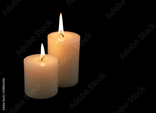 Two burning candles isolated on black background. Copy space for text.