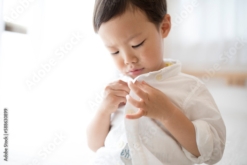 洋服のボタンをとめている男の子