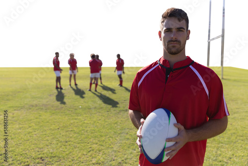 Rugby player holding football at field.