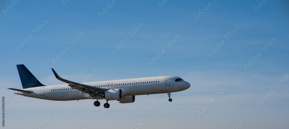 Side view of an airplane landing against a blue sky. Widescreen. 