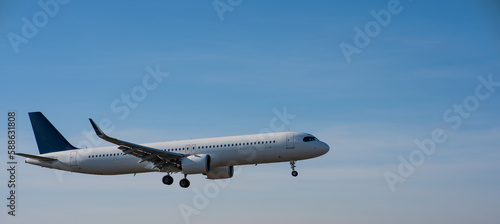 Side view of an airplane landing against a blue sky. Widescreen. 