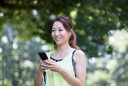 イヤホンをしながらスマホを見るジョギング中の女性 photo