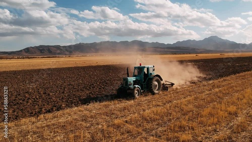 Aerial view tractor plowing field for sowing. Farm tractor with rotary harrow plow preparing land for sowing. Food industry concept. Agriculture. High quality 4k footage